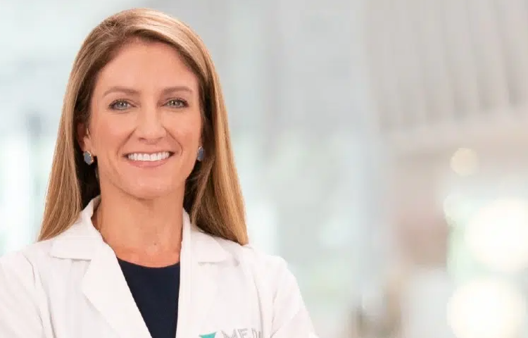 Smiling female doctor in white lab coat with stethoscope, blurred background